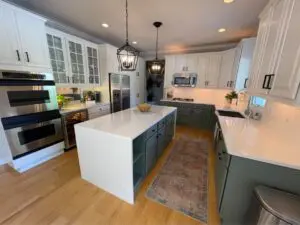 Open-concept kitchen and living area featuring a navy island, farmhouse sink, and brass accents, highlighting a beautiful Kitchen Renovation in Spring Lake, MI.