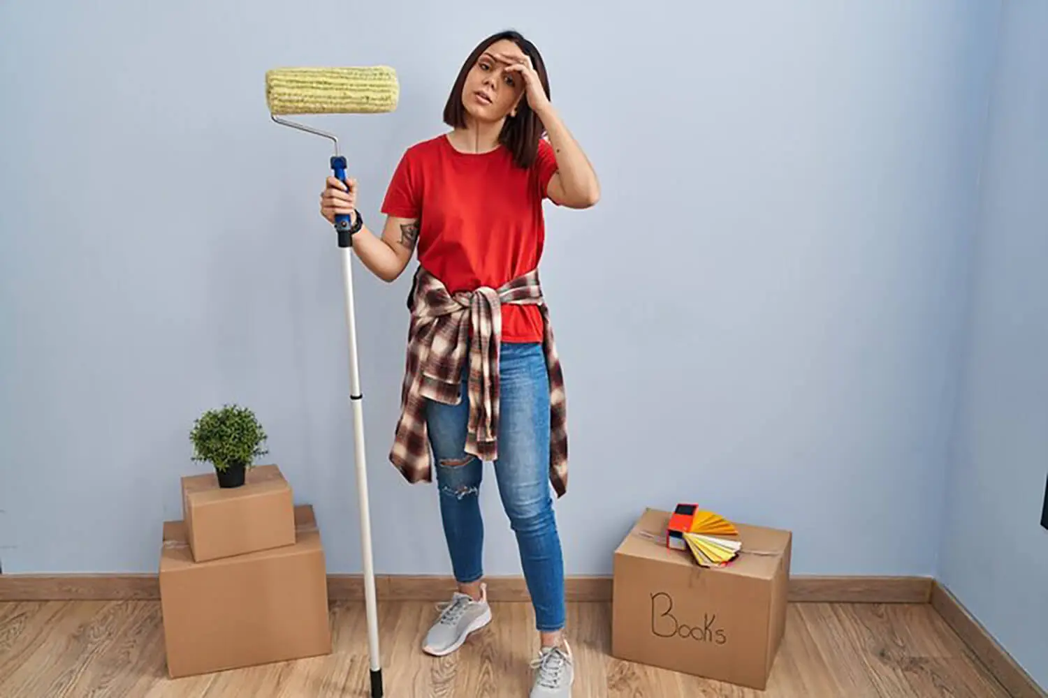 Homeowner holding a paint roller and looking concerned while painting a wall, illustrating how to tell if your home’s interior paint is failing
