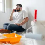 A painter on a job site surrounded by drop cloths and painting tools, the kind of professional communication homeowners should expect after asking the right questions to ask before hiring an interior painter.