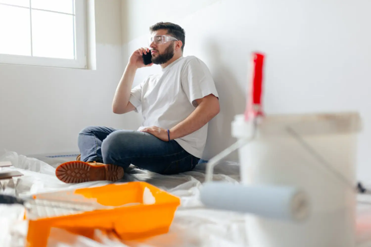 A painter on a job site surrounded by drop cloths and painting tools, the kind of professional communication homeowners should expect after asking the right questions to ask before hiring an interior painter.