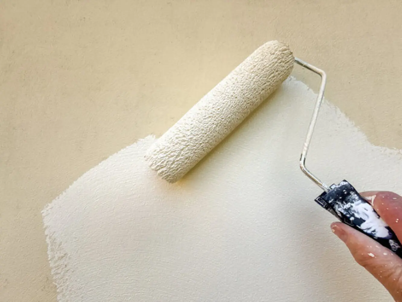 A roller applying a soft, neutral paint finish to an interior wall, showing the subtle sheen difference that matters when choosing the right interior paint finish for homes in Kentwood.