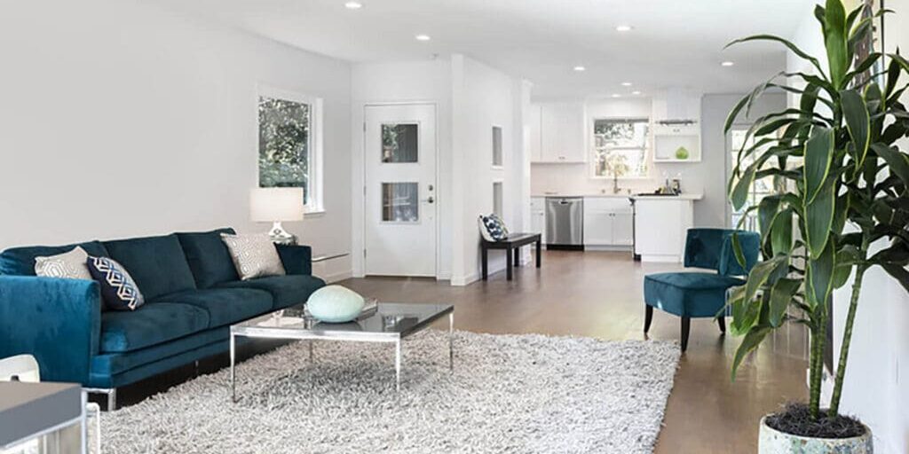 Bright living room with white walls and hardwood floors, showing how professional painters protect furniture and floors during interior projects