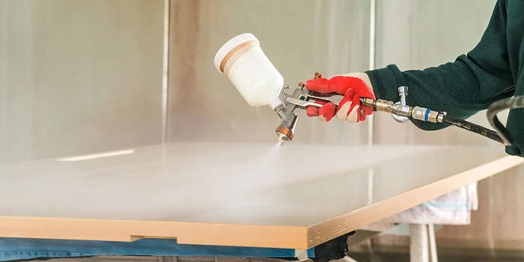 Spraying primer on kitchen cabinet doors as part of how to prepare for a cabinet painting project