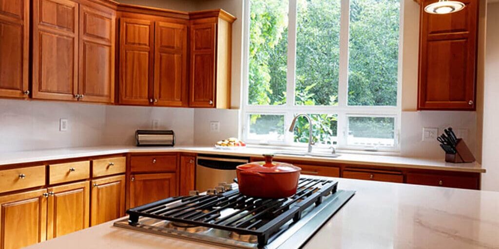 Modern kitchen with warm wood cabinets and smooth finishes, highlighting reasons to hire a professional for cabinet refinishing